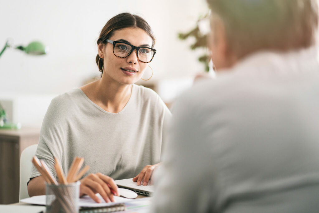 Zwei Personen sitzen sich an einem Schreibtisch gegenüber und besprechen das Basic-Partner Programm.